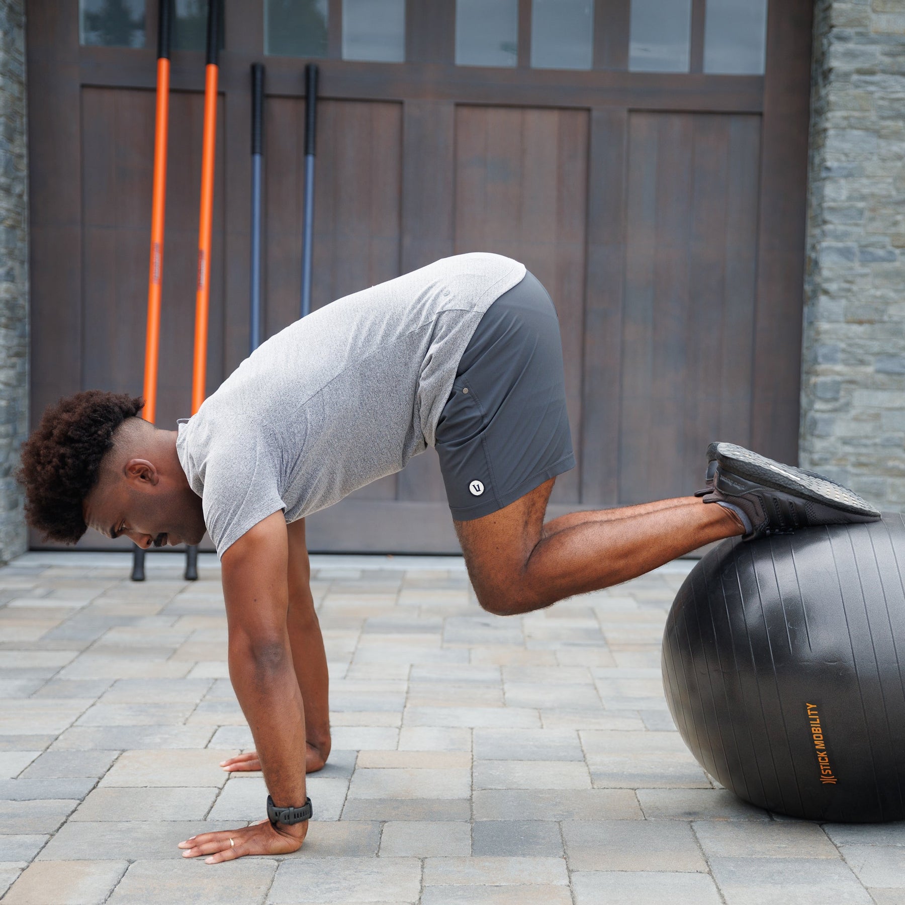 Man in a plank position with hands on the ground and feet on the Exercise Ball with knees pulled in towards their chest