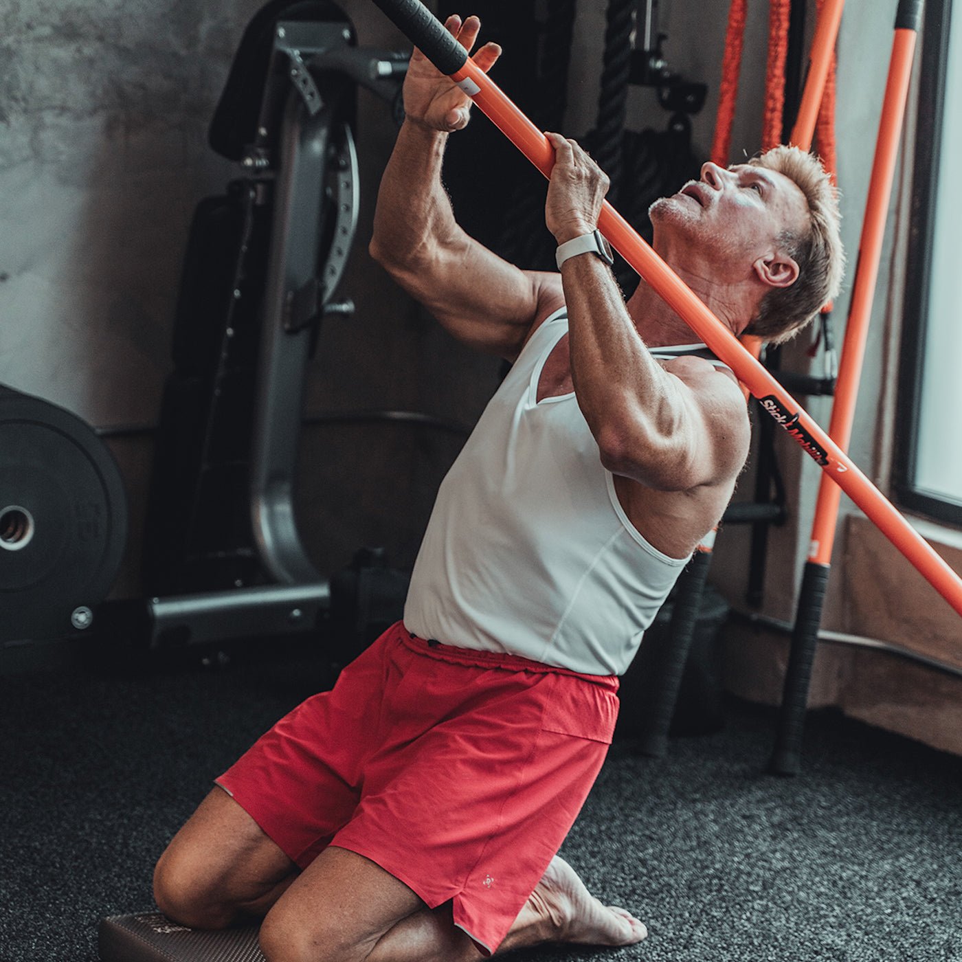 Man performing a kneeling reverse nordic with a Training Stick