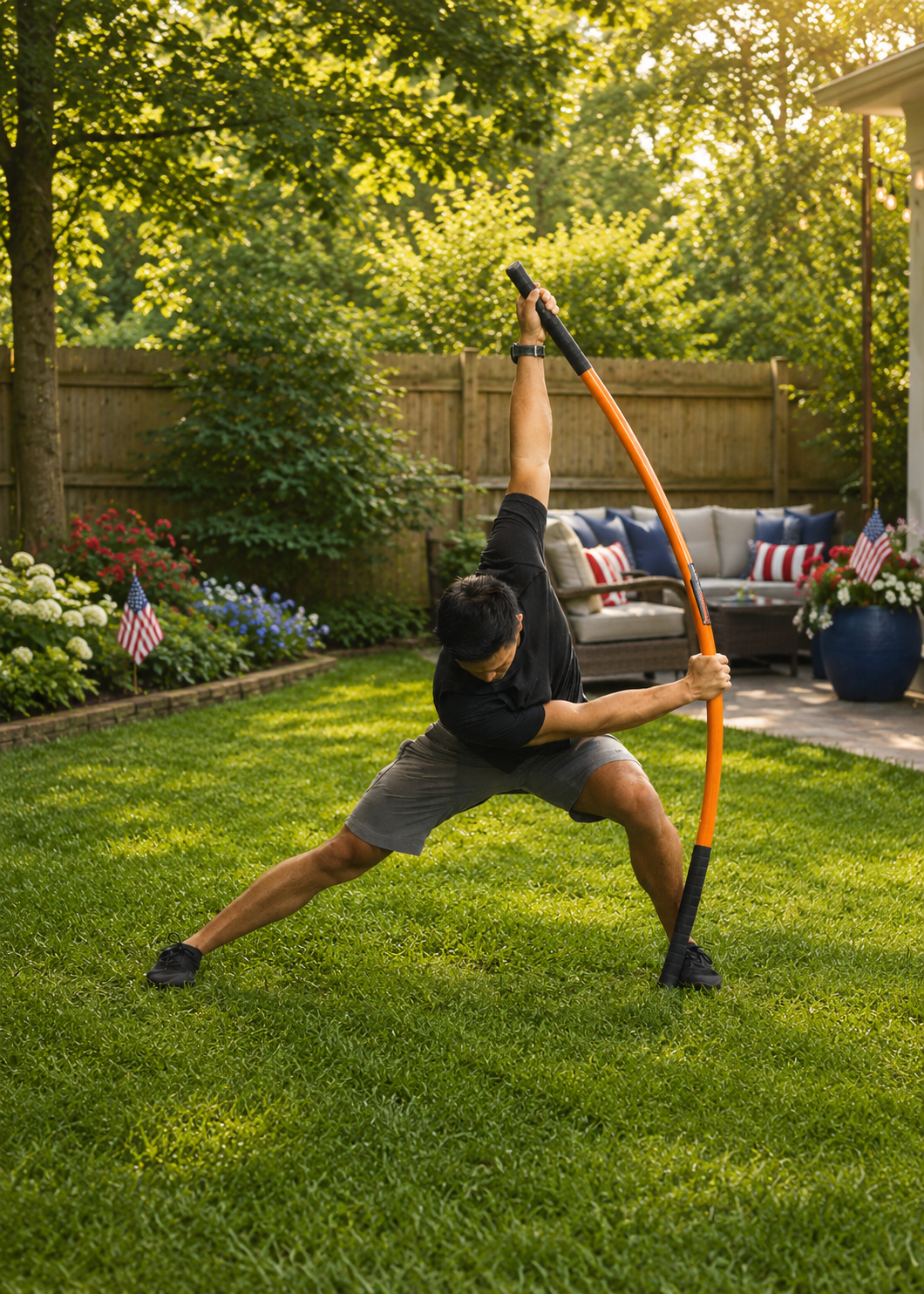 Person using a training stick in a backyard setting with a wooden fence and American flags.