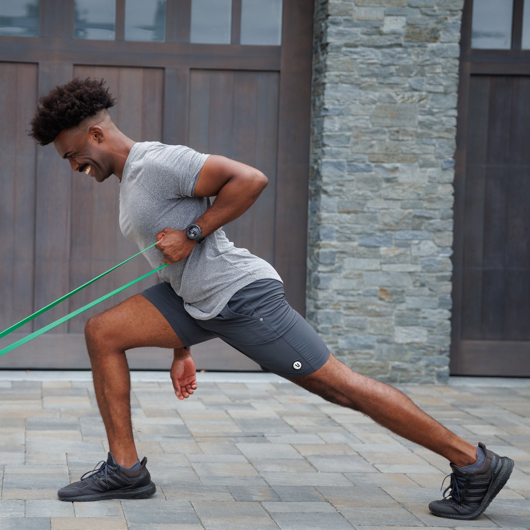 Man smiling in forward lunge while pulling the Resistance Band with one arm