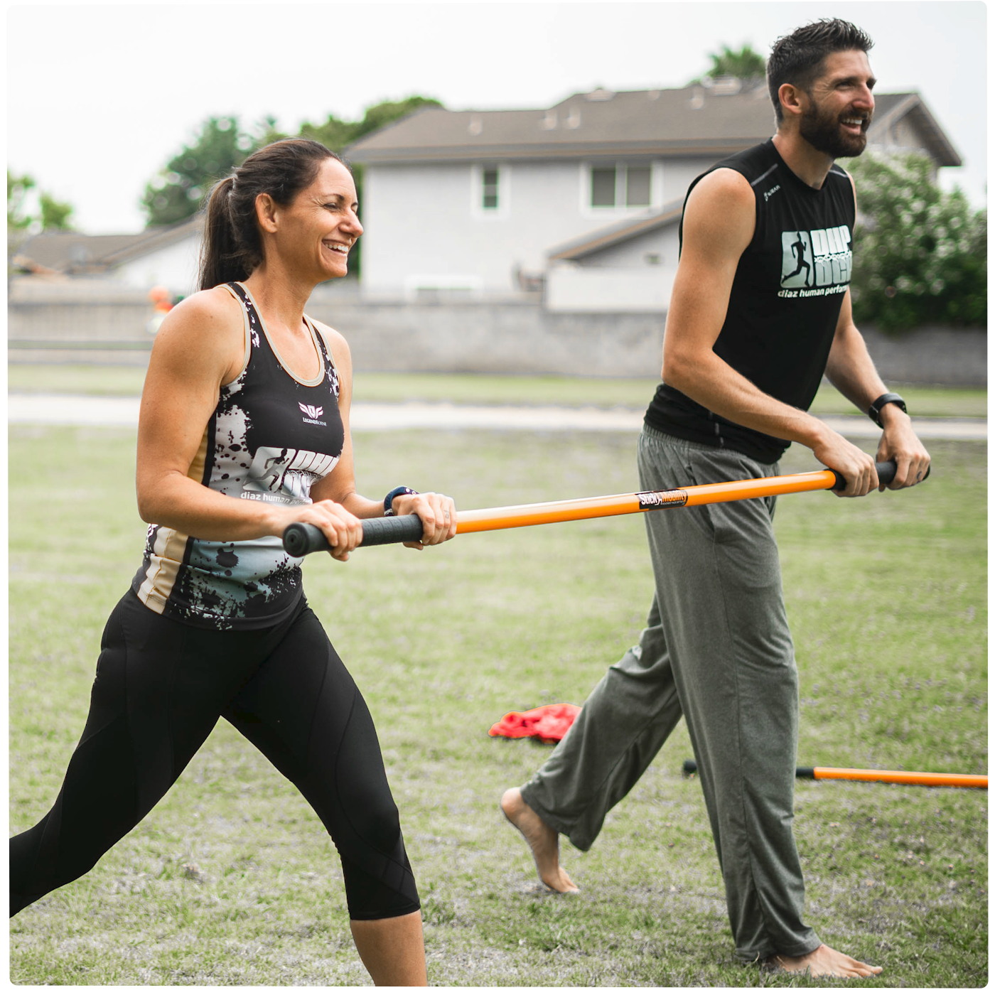 Man and woman smiling while each holding an end of a Training Stick and walking forward.