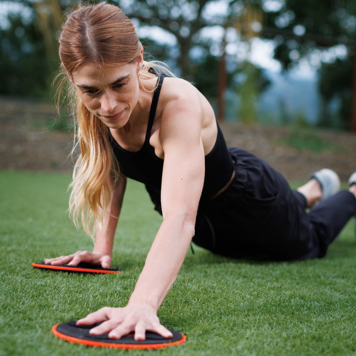 Woman in a kneeling plank with a TriSlider under each hand