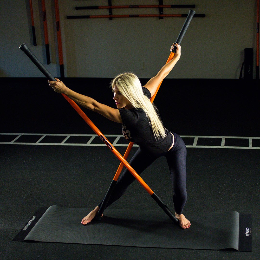 Woman performing the Stick Mobility monkey hang with swinging with two Training Sticks.
