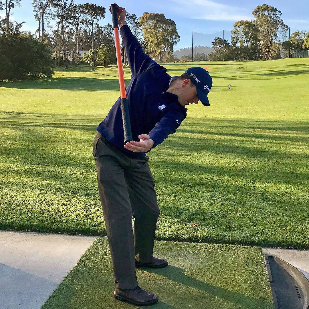 A man mimicking a golf swing with the Training Stick.