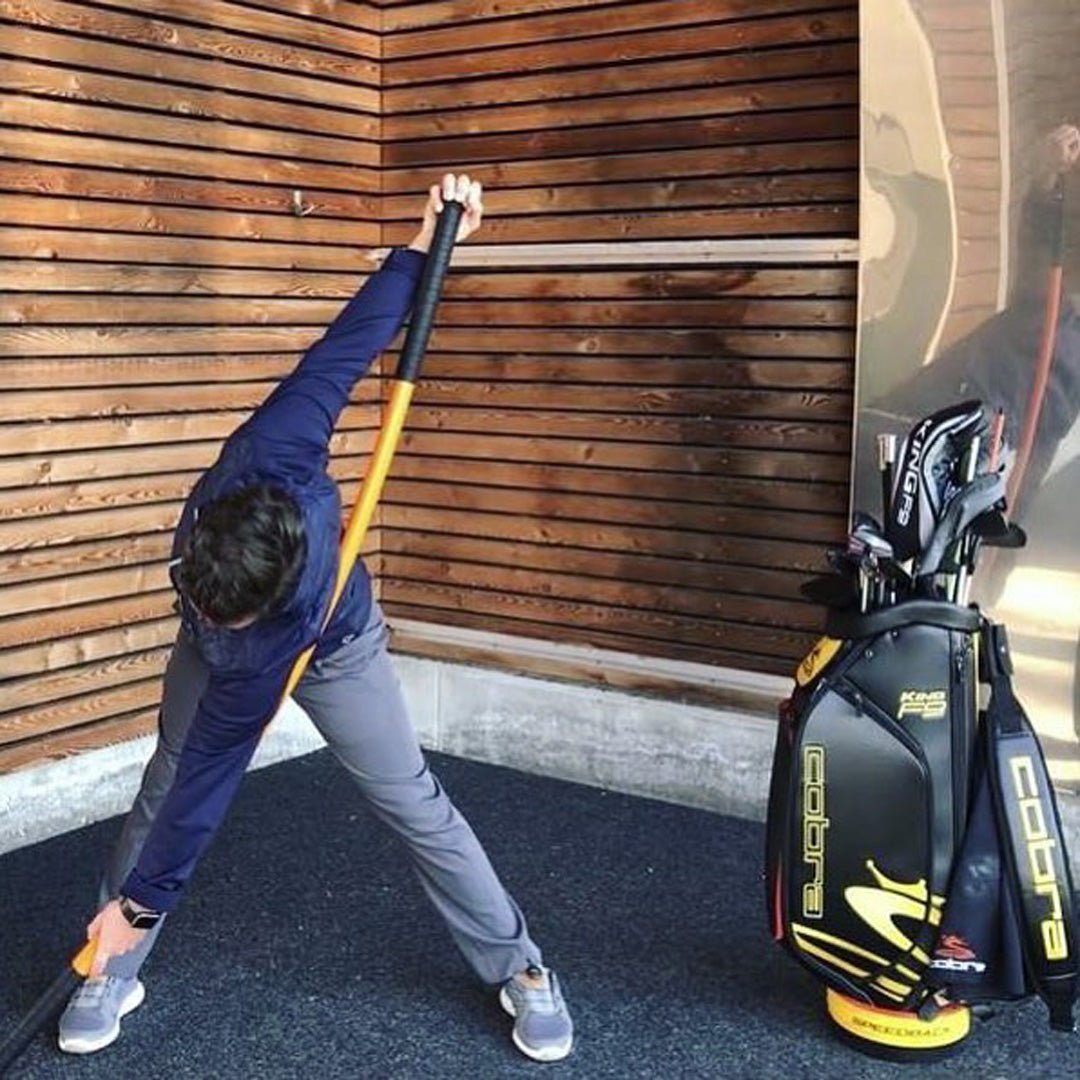 A man stretching with a Training Stick next to his golf clubs.