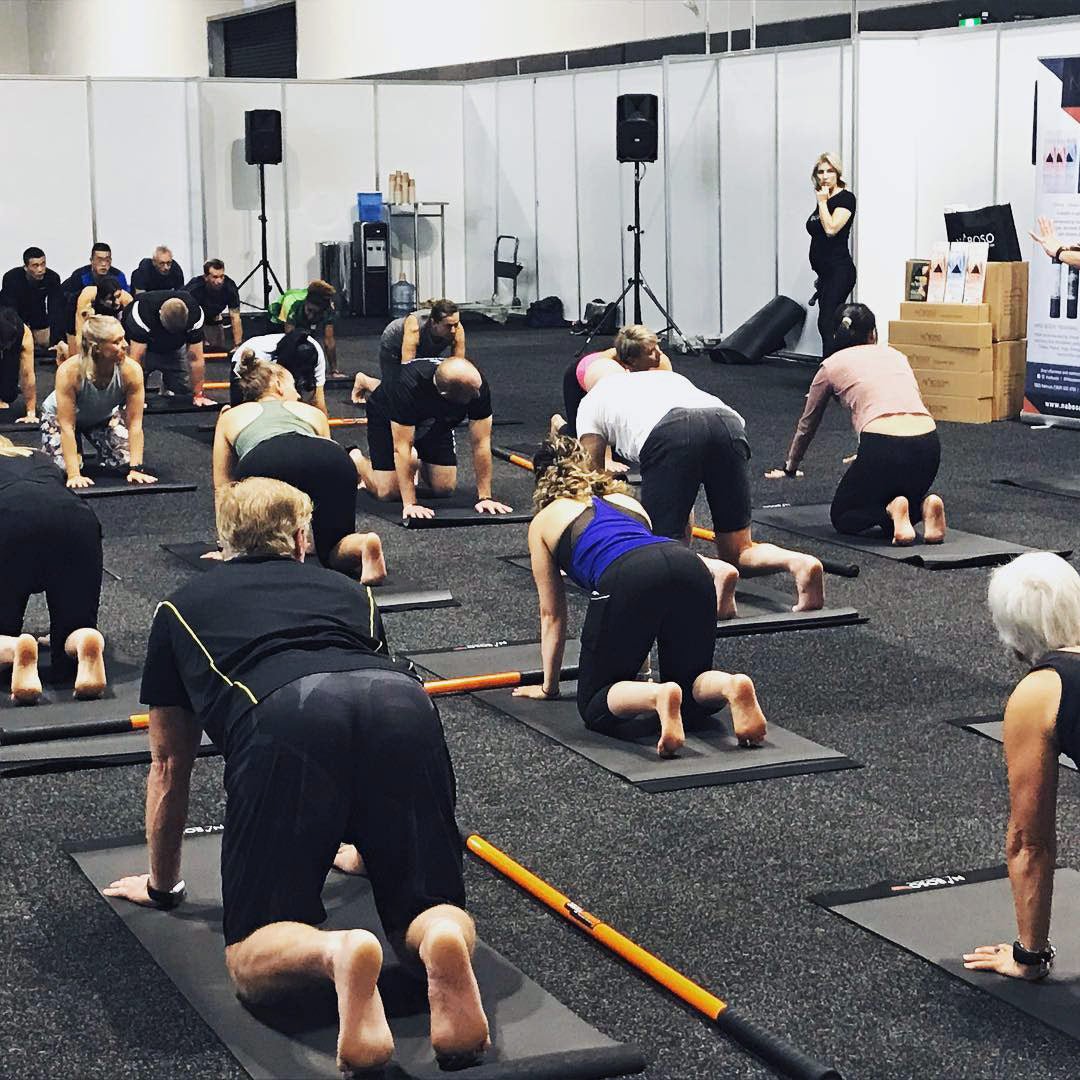 A group of people stretching on the ground with Training Sticks.