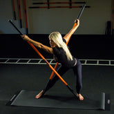 A woman performing an exercise with two Training Sticks.