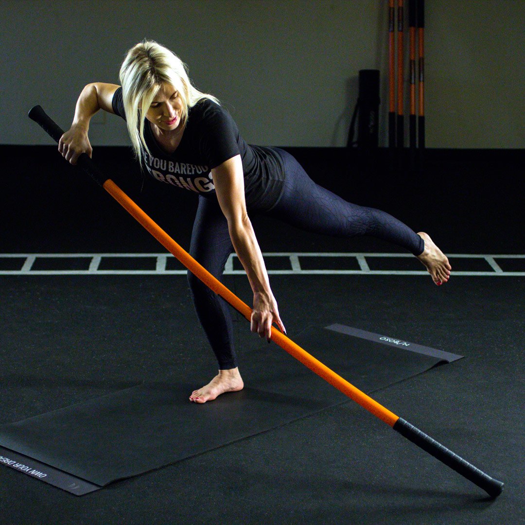 A woman perform an exercise with a Training Stick.