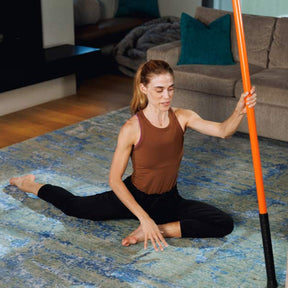 Woman stretching in the pigeon pose with Stick Mobility Training Stick