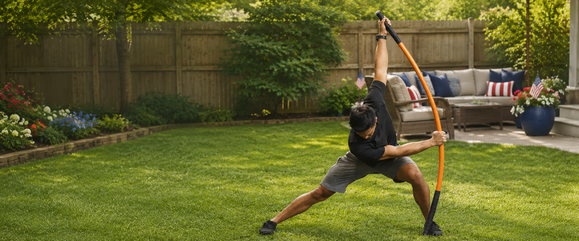 Person using a training stick in a backyard setting with a wooden fence and outdoor furniture.