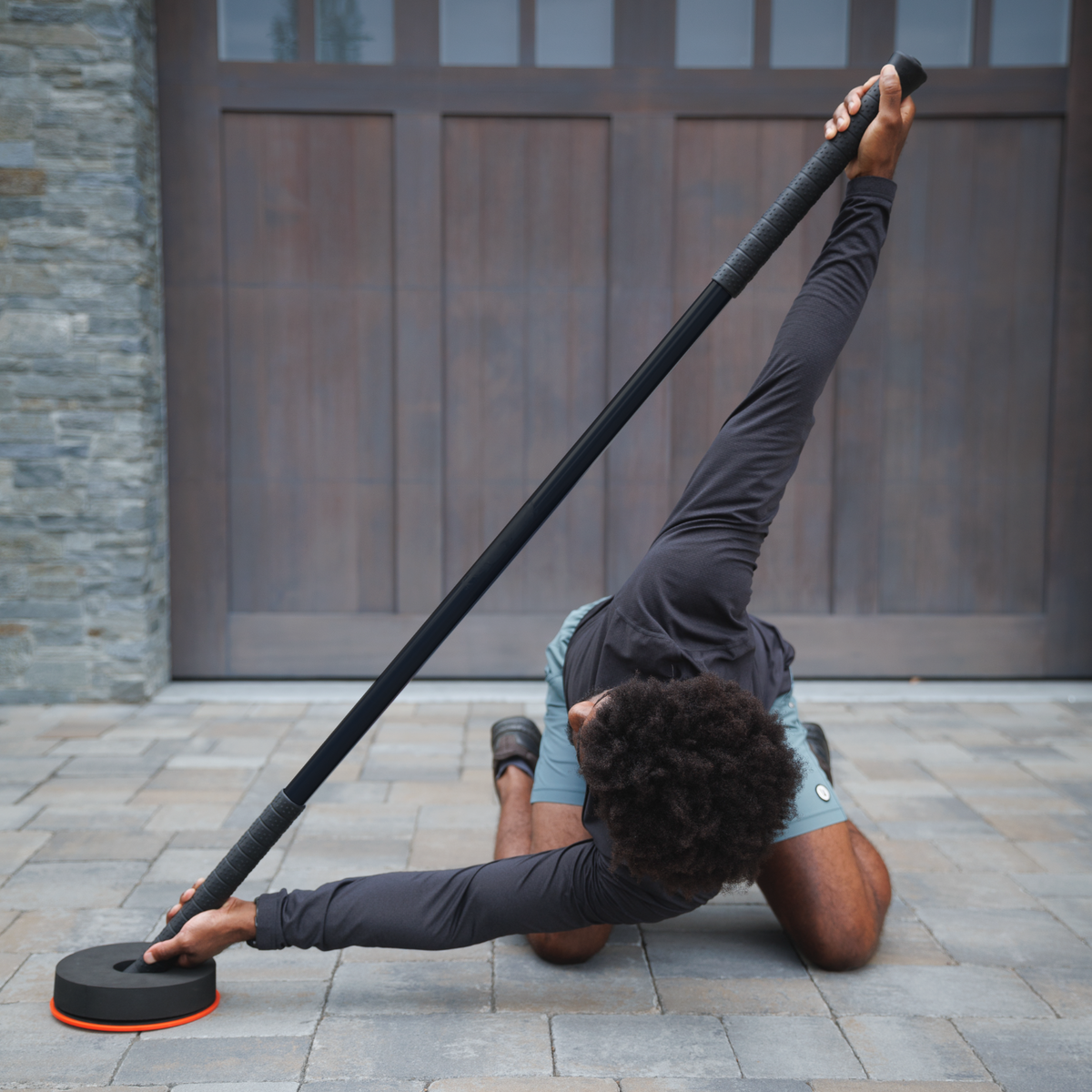 Person using a resistance band outdoors on a stone patio.