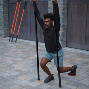 Man using resistance poles for exercise on a paved area.