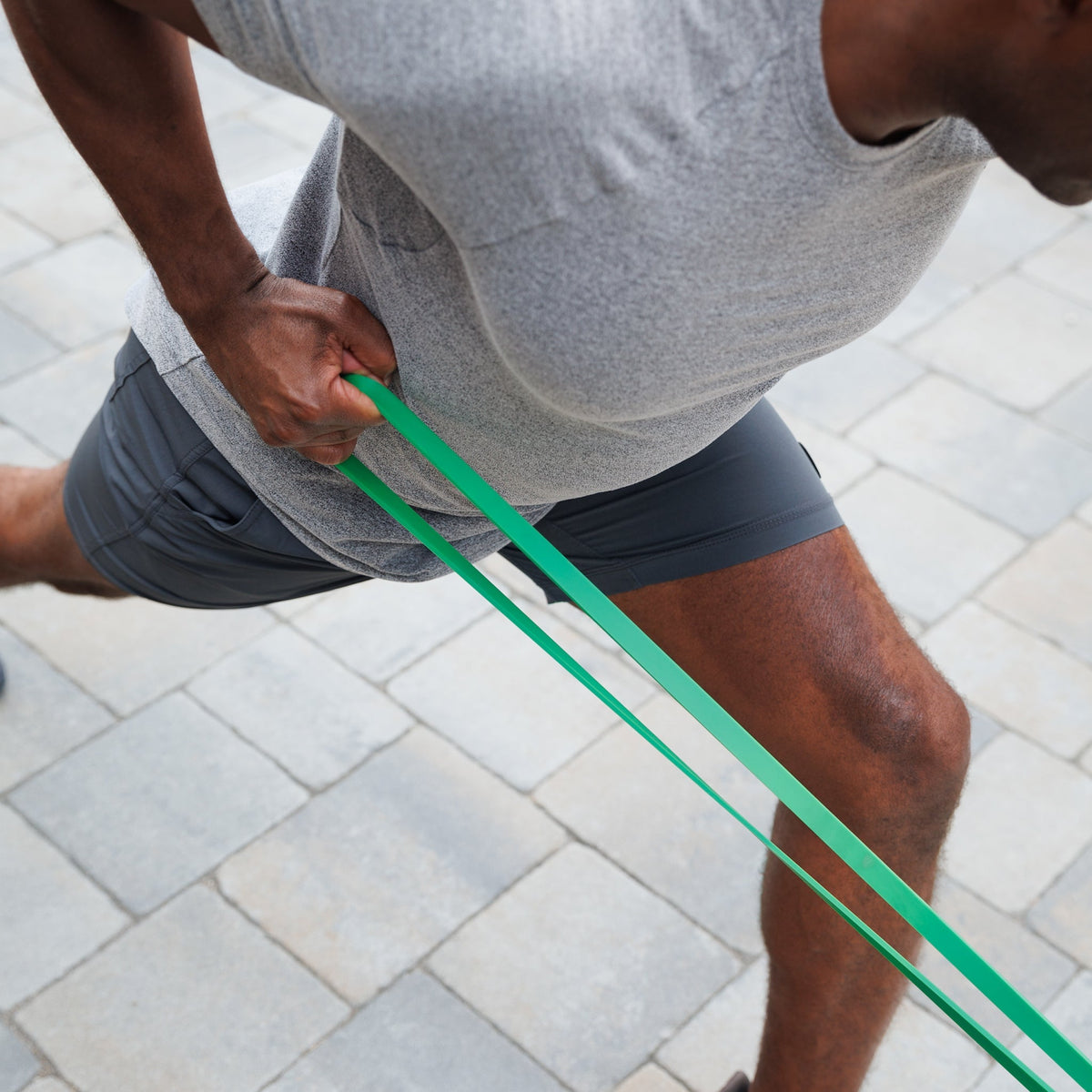 Man in a forward lunge pulling the Resistance Band with one arm