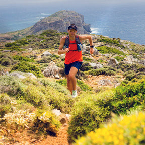 A runner sprinting up a mountain, showcasing determination and athleticism while wearing a Stick Mobility hat, symbolizing endurance and mobility-focused training.