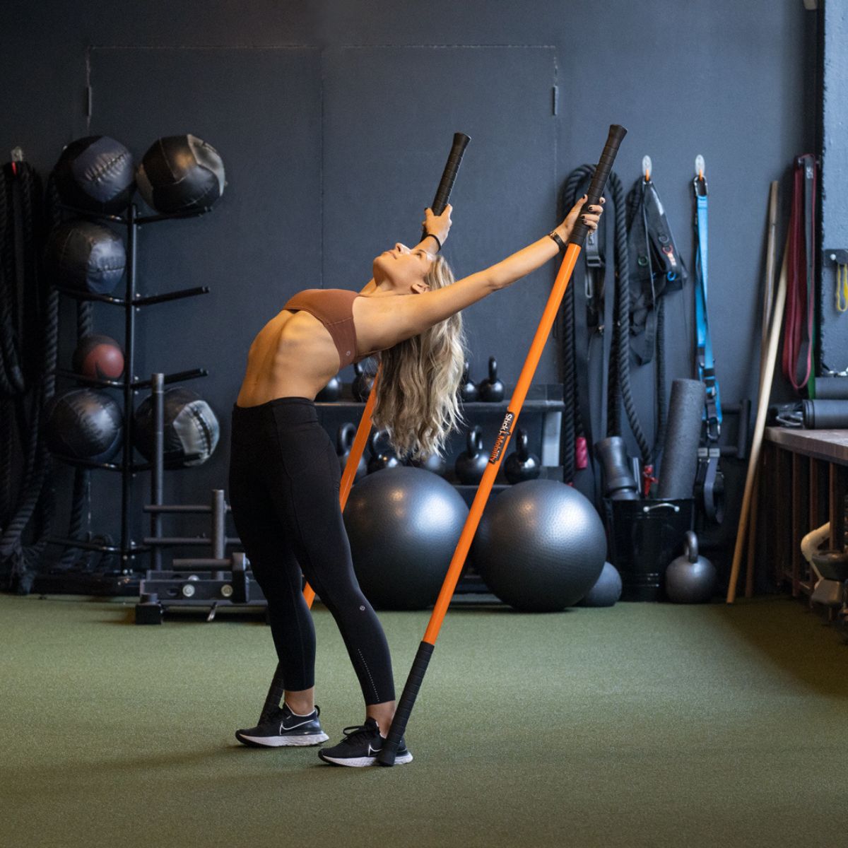 Woman performing an exercise with two Training Sticks.