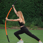 Woman performing a forward lunge while bending the Training Stick forward.