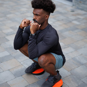 Man performing a squat while balancing on a TriSlider under each foot